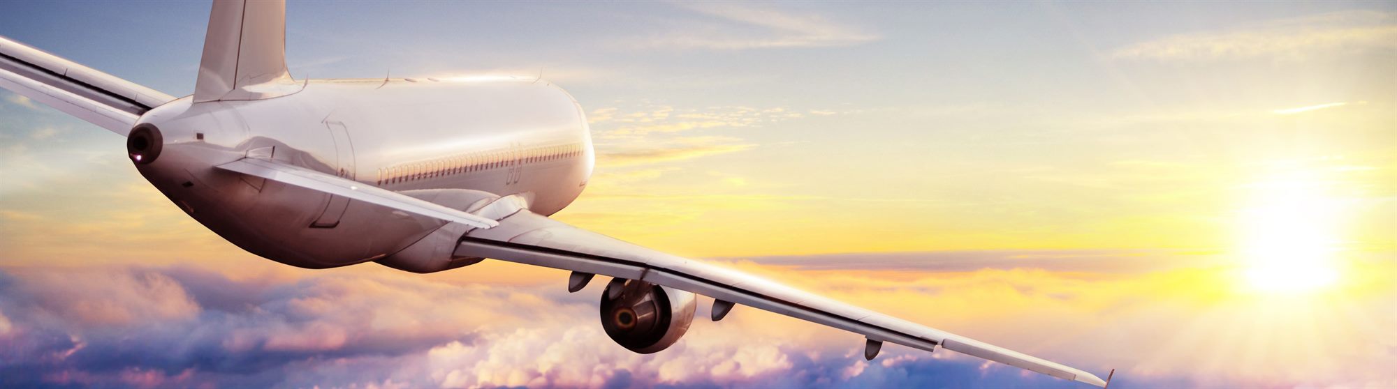 An aircraft climbing away into a golden evening sky